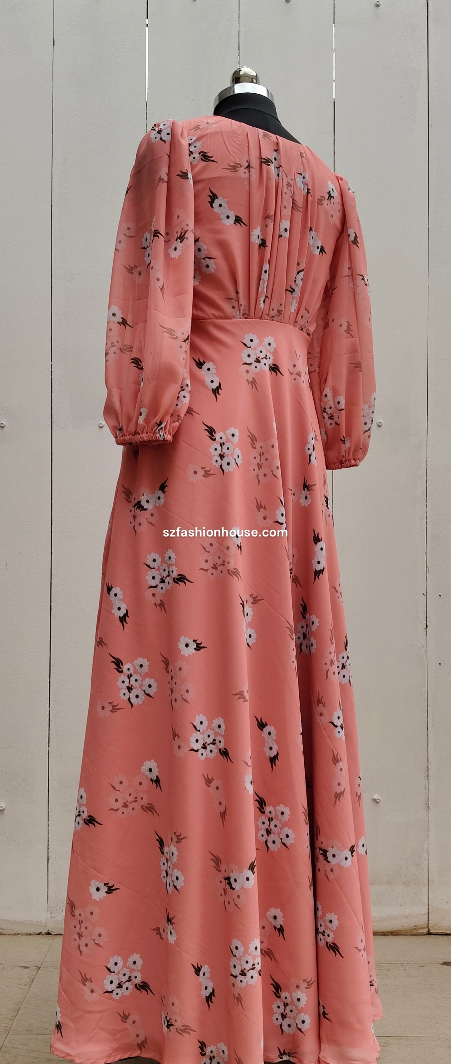 Pink floral dress on a mannequin against a wooden background