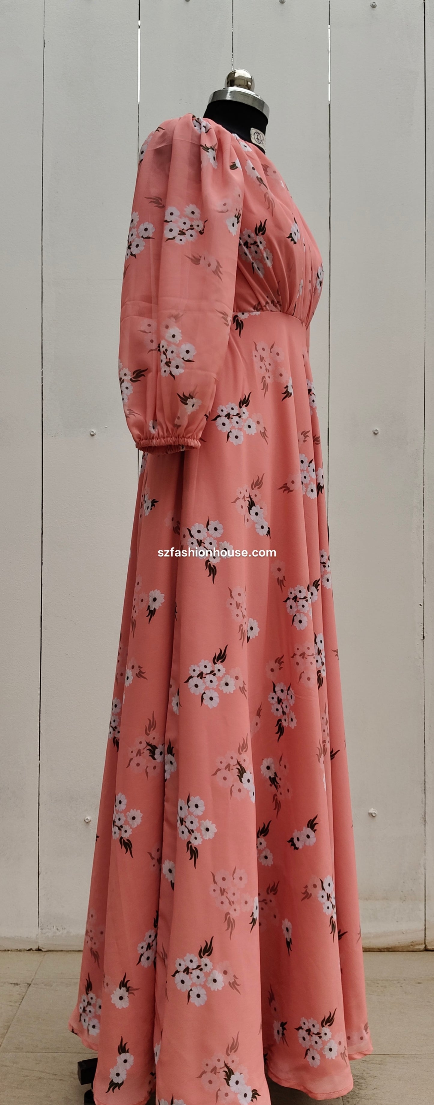 Pink floral dress on a mannequin against a white wooden panel background