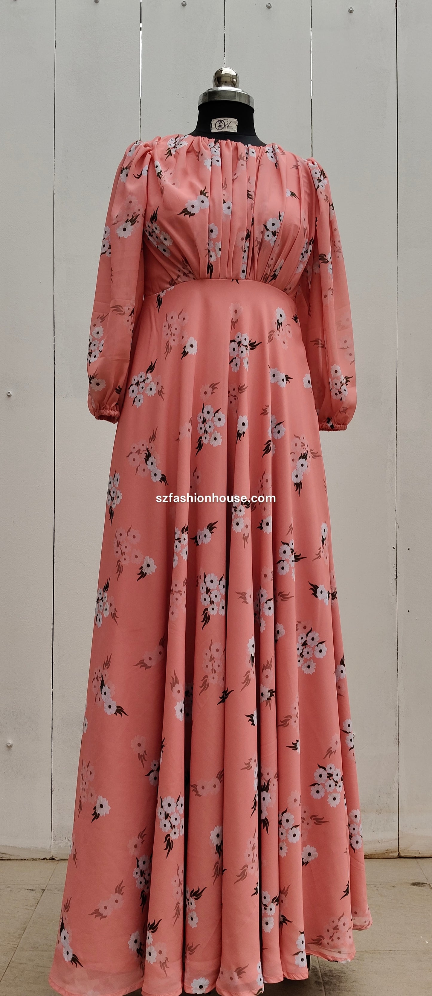 Pink floral dress on a mannequin against a white wooden panel background