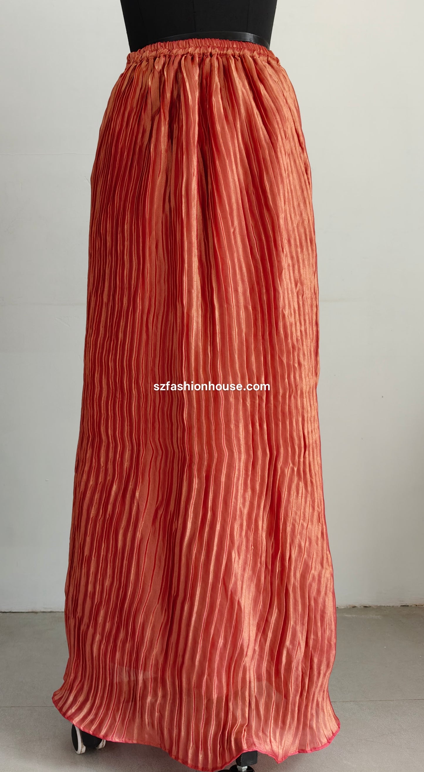 Long rust-colored pleated skirt on a plain background